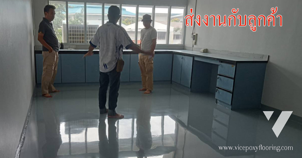 ทีมงาน VIC ยืนตรวจรับงานพื้น Epoxy Self-Leveling สีเทาผิวเงาร่วมกับลูกค้าในห้องทำงาน พื้นสะท้อนเงาคนและเคาน์เตอร์ได้เต็มตัว